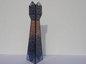 Dit glazen object is de koningin in de serie 'Schaakstukken'. Gemaakt van blank glas dat is ingekleurd en met een tiffany-techniek aan elkaar gezet.